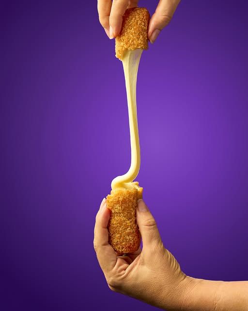 Dedo de queso apanado abriéndose en hilo sobre fondo morado